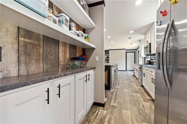 kitchen with appliances with stainless steel finishes, light hardwood / wood-style floors, and white cabinetry