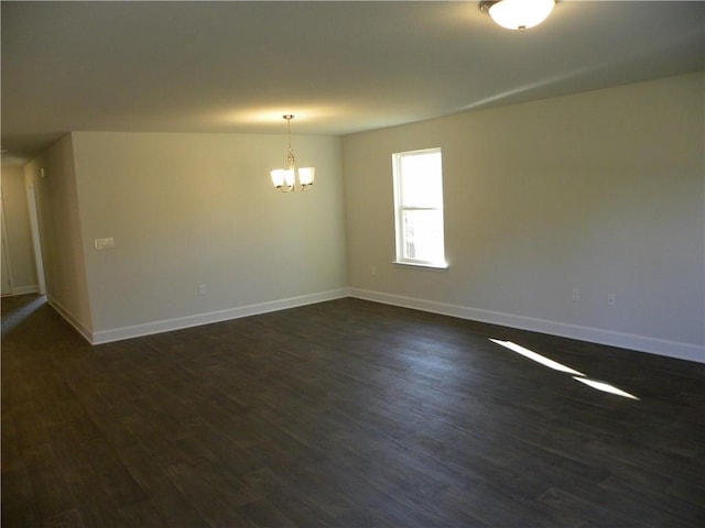 empty room featuring dark hardwood / wood-style floors and a notable chandelier