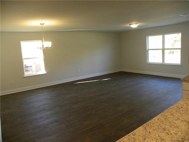 spare room with dark wood-type flooring and a notable chandelier