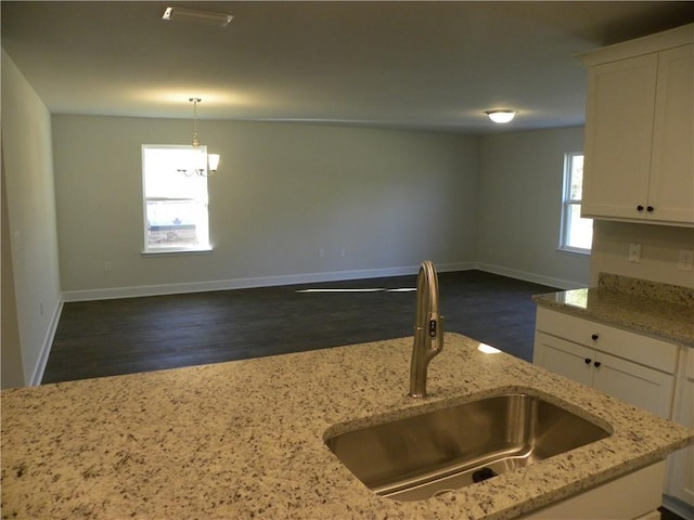 kitchen featuring white cabinetry, light stone counters, sink, and decorative light fixtures