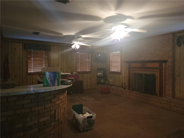 living room featuring a textured ceiling, ceiling fan, and wooden walls