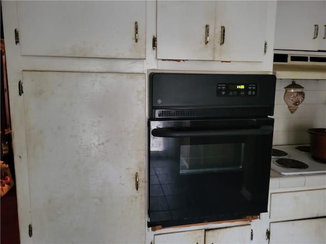 interior details with white cabinets, oven, white stovetop, and decorative backsplash