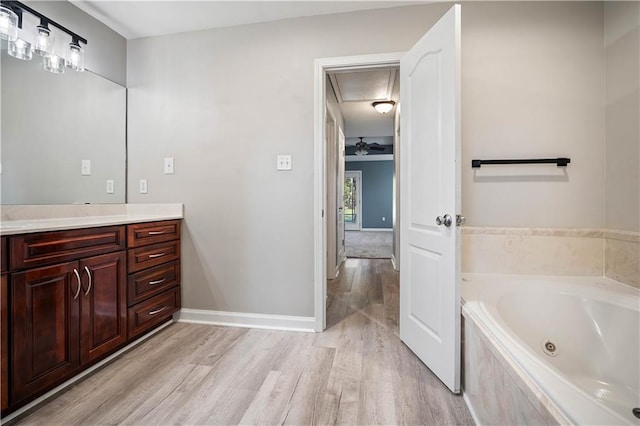 bathroom with tiled bath, hardwood / wood-style floors, and vanity