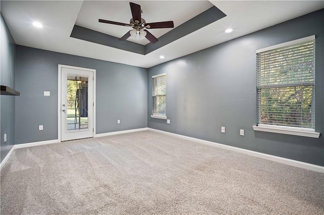 carpeted empty room with baseboards, a ceiling fan, recessed lighting, and a tray ceiling