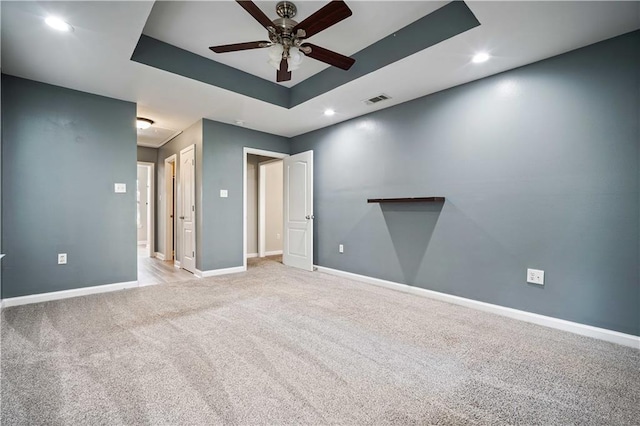 unfurnished room featuring a ceiling fan, attic access, a raised ceiling, recessed lighting, and baseboards