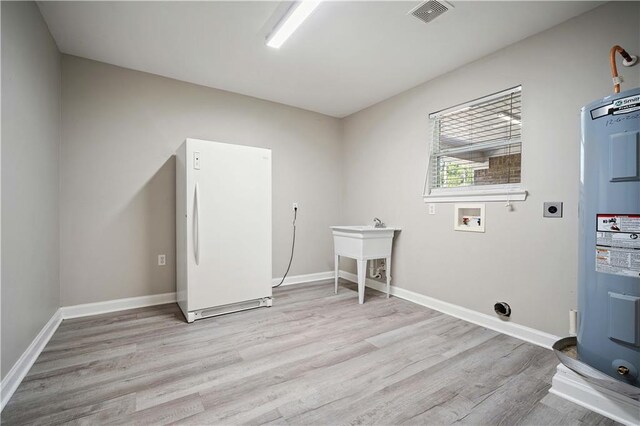 clothes washing area with water heater, light wood-type flooring, electric dryer hookup, and washer hookup