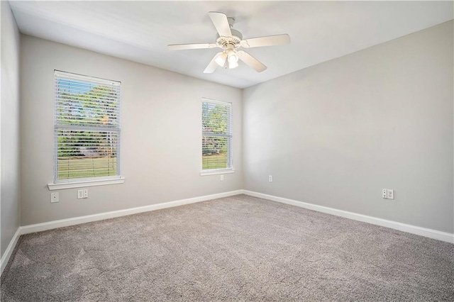 carpeted spare room featuring plenty of natural light, baseboards, and a ceiling fan