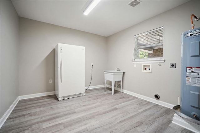 clothes washing area featuring electric dryer hookup, wood finished floors, water heater, washer hookup, and baseboards
