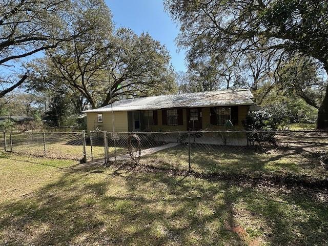 rear view of house featuring a fenced front yard, a lawn, and a gate