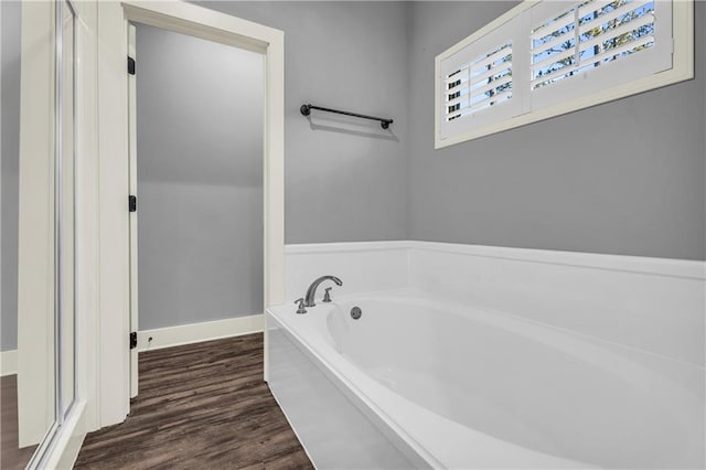 bathroom with hardwood / wood-style flooring and a tub