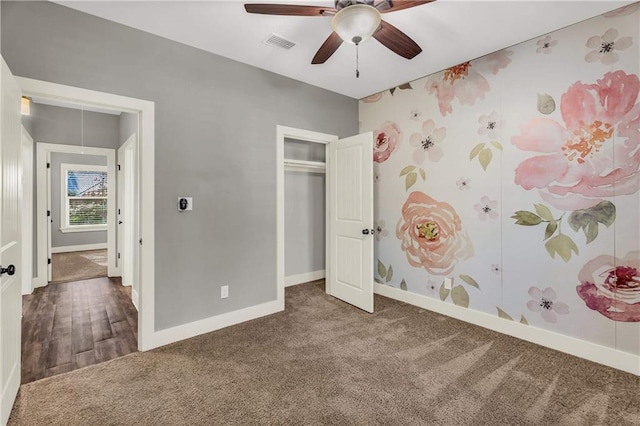 unfurnished bedroom with ceiling fan, a closet, and dark colored carpet