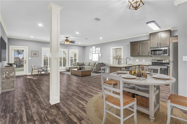 dining space with dark hardwood / wood-style flooring, sink, crown molding, and ornate columns