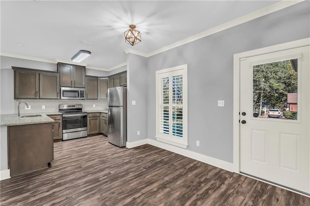 kitchen featuring appliances with stainless steel finishes, dark hardwood / wood-style floors, sink, ornamental molding, and light stone counters