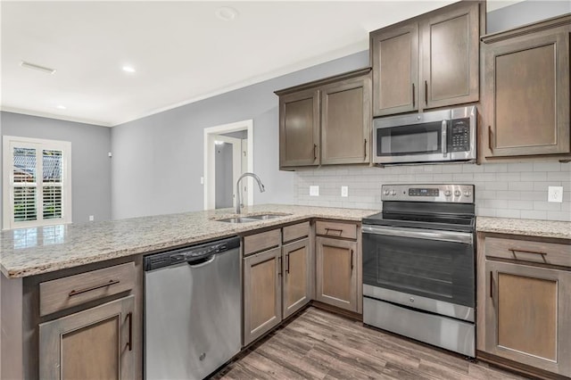 kitchen featuring dark wood-type flooring, sink, appliances with stainless steel finishes, kitchen peninsula, and decorative backsplash