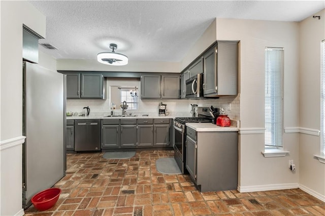 kitchen featuring stainless steel appliances, light countertops, a sink, and decorative backsplash