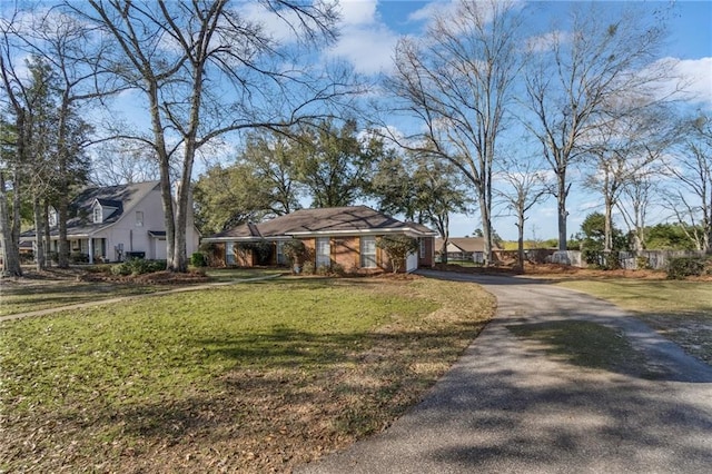 view of front of house featuring aphalt driveway, an attached garage, and a front lawn