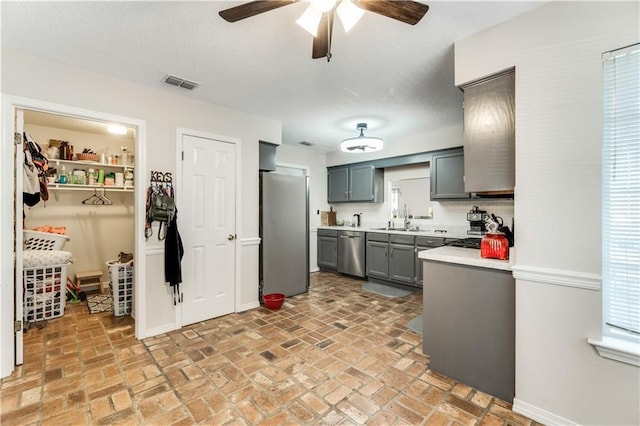 kitchen with gray cabinetry, a sink, visible vents, light countertops, and appliances with stainless steel finishes