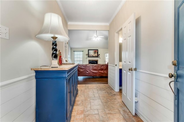 interior space featuring ornamental molding, stone finish flooring, and a wainscoted wall