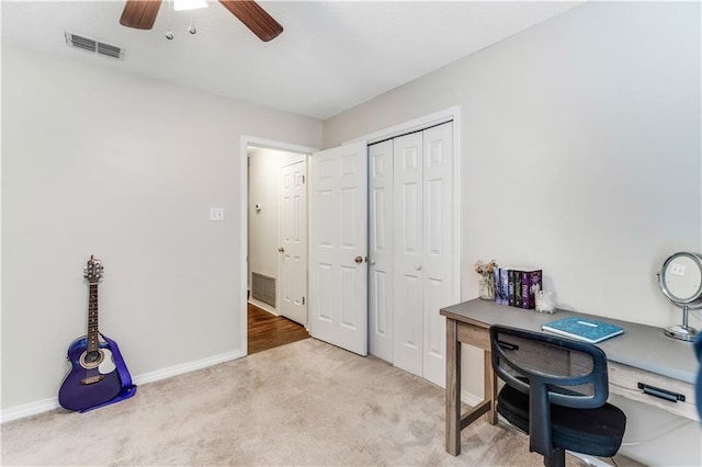 office space featuring carpet floors, baseboards, visible vents, and a ceiling fan