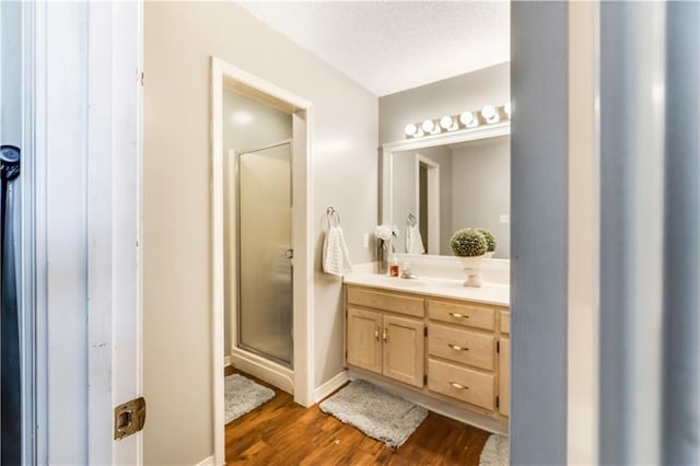 full bath with a shower stall, a textured ceiling, wood finished floors, and vanity