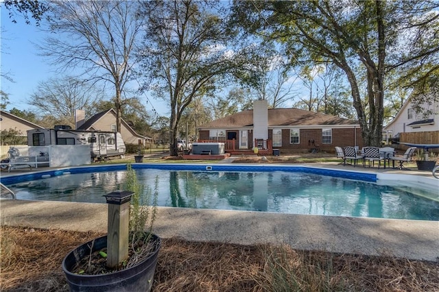 outdoor pool with a patio area, fence, and a hot tub