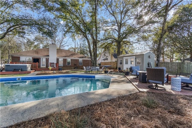 view of swimming pool featuring a deck, an outbuilding, fence, and a hot tub