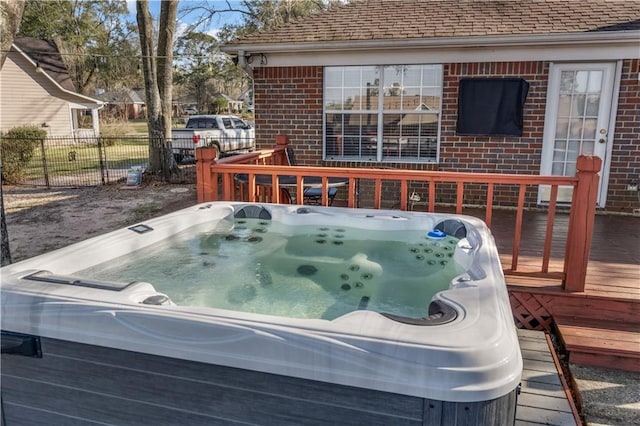 wooden deck with a hot tub and fence