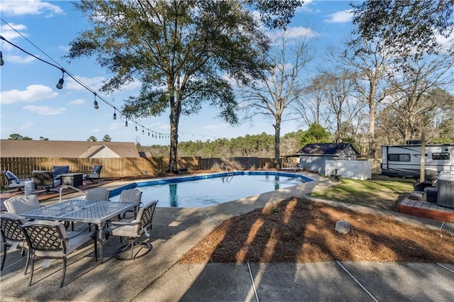 view of swimming pool featuring a fenced in pool, a fenced backyard, an outbuilding, outdoor dining area, and a patio area