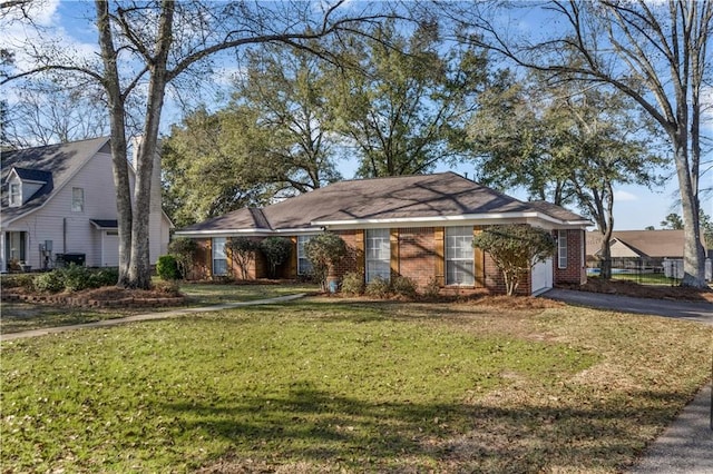 single story home with a front yard, brick siding, and driveway