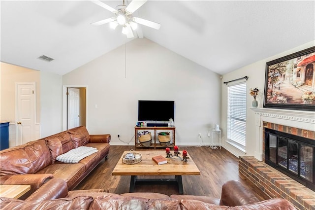 living room featuring a fireplace, lofted ceiling, visible vents, ceiling fan, and wood finished floors