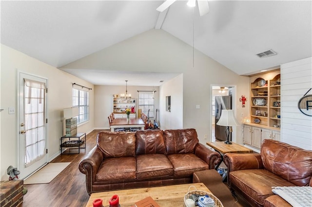 living area with visible vents, dark wood finished floors, vaulted ceiling, built in shelves, and ceiling fan with notable chandelier