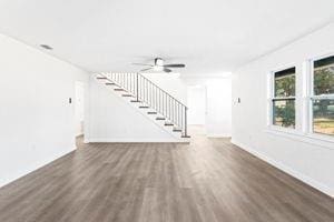 unfurnished living room featuring ceiling fan and dark hardwood / wood-style flooring