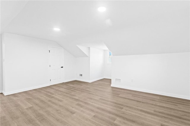 bonus room featuring light wood-type flooring and vaulted ceiling