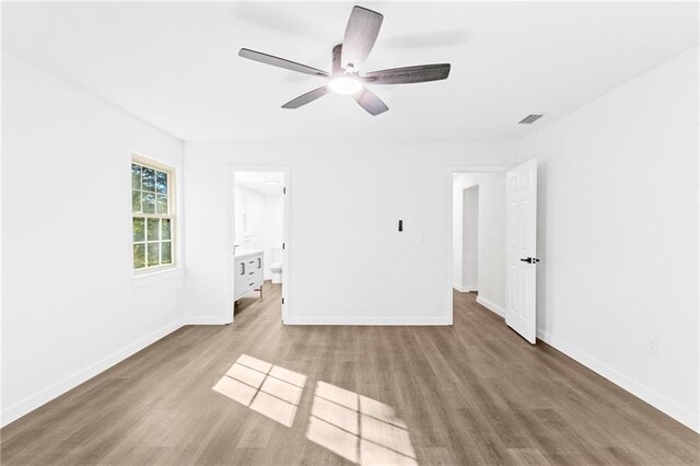 unfurnished bedroom featuring wood-type flooring, ensuite bath, and ceiling fan