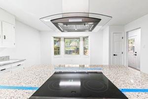 kitchen with white cabinets, plenty of natural light, light stone countertops, and black electric cooktop