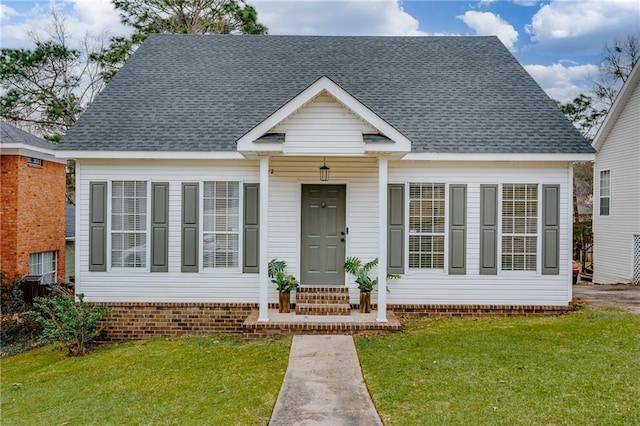 view of front of property featuring entry steps, a front lawn, and roof with shingles