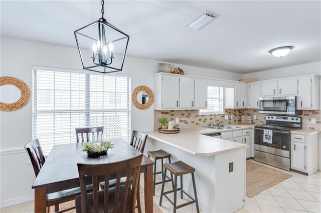 kitchen featuring appliances with stainless steel finishes, pendant lighting, light countertops, and white cabinets