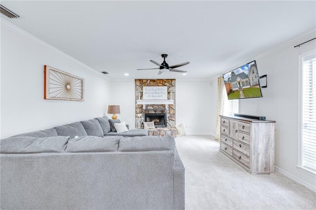 living room featuring light carpet, visible vents, a ceiling fan, ornamental molding, and a stone fireplace