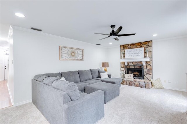 living room with light carpet, visible vents, a ceiling fan, crown molding, and a stone fireplace