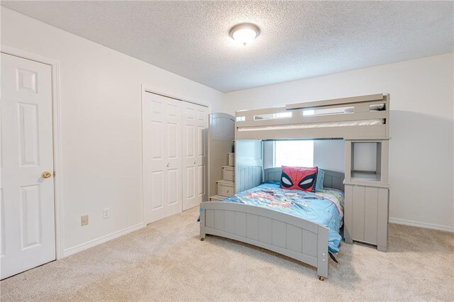 bedroom featuring baseboards, a textured ceiling, and light colored carpet