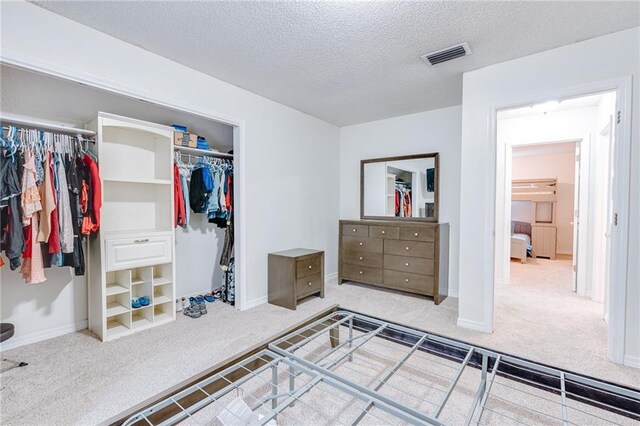 bedroom featuring baseboards, visible vents, a textured ceiling, and light colored carpet