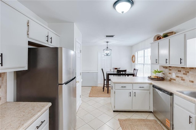 kitchen featuring light countertops, appliances with stainless steel finishes, white cabinetry, and decorative light fixtures