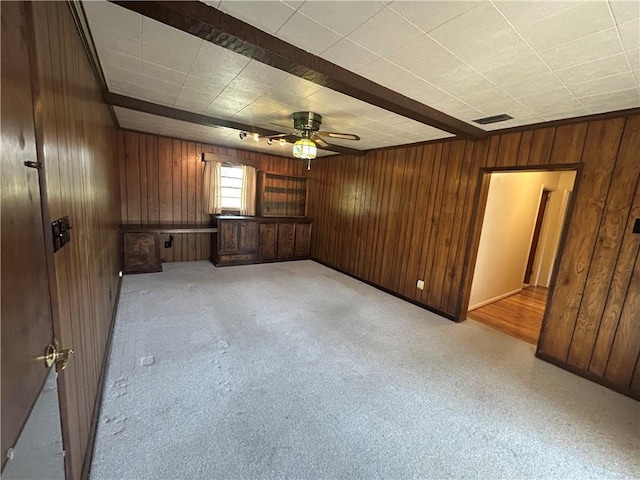 empty room featuring wood walls, visible vents, and a ceiling fan