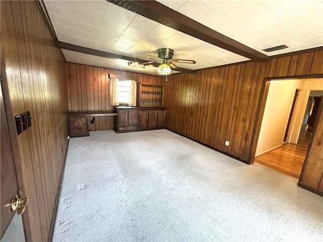 unfurnished room with wooden walls, visible vents, and a ceiling fan