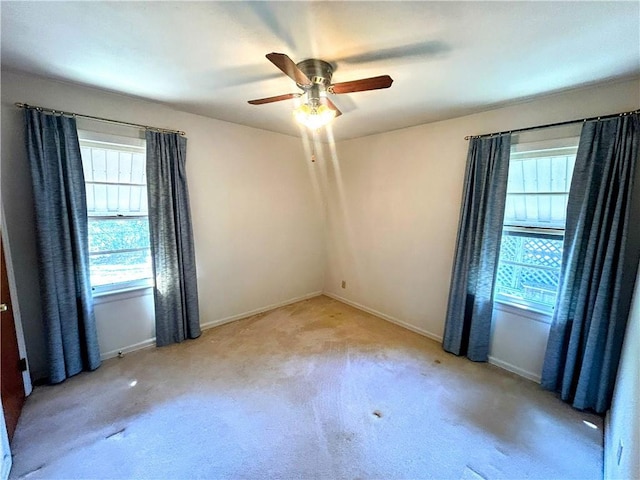 spare room featuring light carpet, baseboards, and a ceiling fan