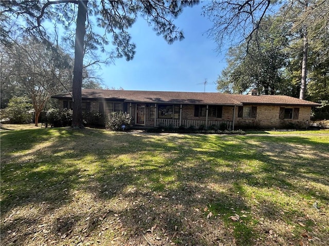 rear view of property with brick siding and a yard