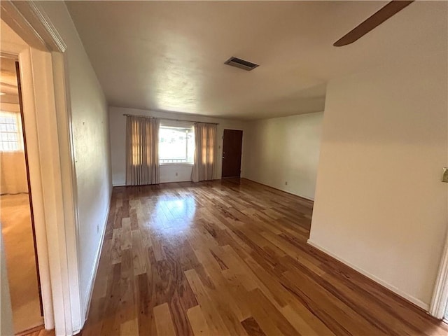 unfurnished room with baseboards, visible vents, and wood finished floors