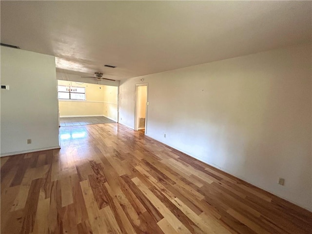 unfurnished room with visible vents, a ceiling fan, and wood finished floors