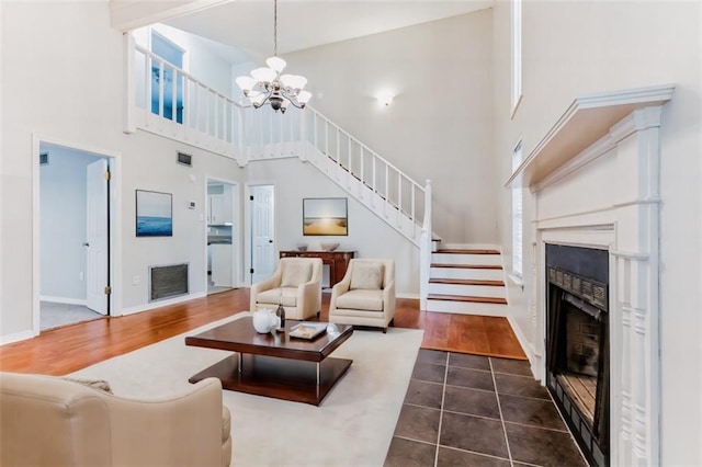 living room with a towering ceiling, dark wood-type flooring, and a chandelier