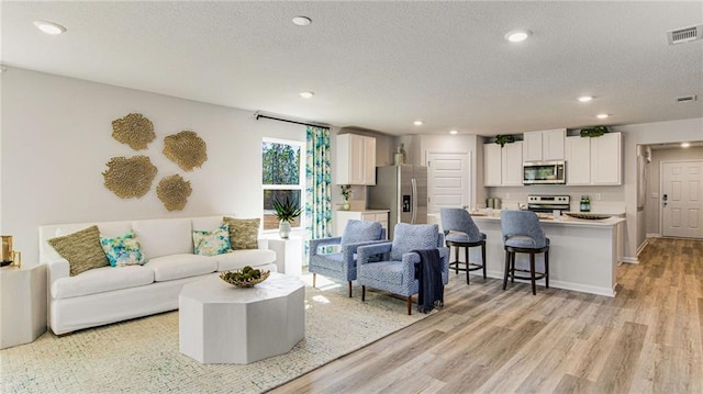 living room with light hardwood / wood-style floors and a textured ceiling